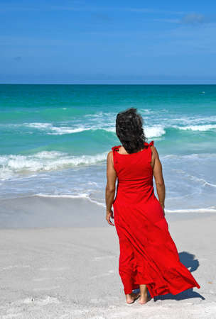 Beautiful Mature Woman Wearing a Red Summer Dress on the Beachの写真素材