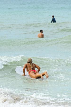 HOLMES BEACH, ANNA MARIA ISLAND, FL / USA -  October 4, 2013: Young Woman with Friends Surfing on Anna Maria Island taking advantage of the larger than normal waves in the Gulf of Mexico.のeditorial素材