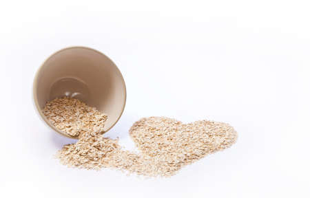 Rolled oats pouring out of a bowl into a heart shapeの写真素材