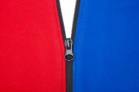 Plain opening black zipper on a red and blue jacket against a white background