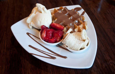 Premium chocolate waffle with strawberry and banana topping with vanilla icecreamの写真素材