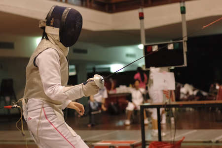 Foil swordman fighting in fencing matchの写真素材