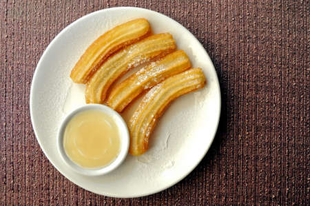 Fresh made Spanish churros with white chocolate dipping suaceの写真素材