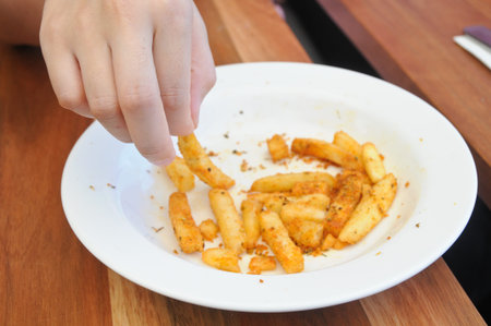 Finger picking golden french fries from a plateの写真素材