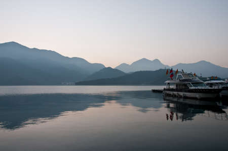 Nantou Taiwan  February 1 2015: A tourist boat is saling calmly in Sun Moon Lake in Nantou province in Taiwan. This photo is taken in the early morning. There is a fog above the mountain with cold temperature.のeditorial素材