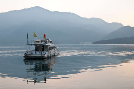 Nantou Taiwan  February 1 2015: A tourist boat is saling in Sun Moon Lake in Nantou province in Taiwan. This photo is taken in the early morning. There is a fog above the mountain with cold temperature.のeditorial素材