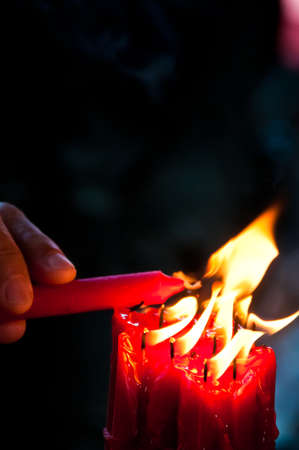 Hand lit a red bright candleの写真素材