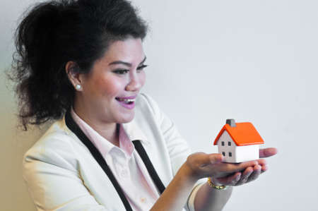 Woman smile and hold a house model on white backgroundの写真素材
