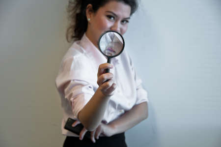Business woman hold magnifier and a mobile phoneの写真素材