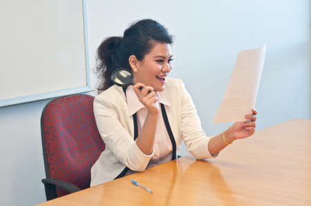 Business woman holds magnifier and is happyの写真素材