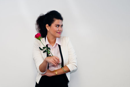 Business woman turn face left and hold red roseの写真素材