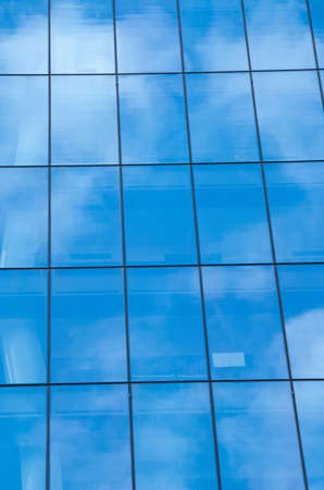 Reflection of blue sky on window glass office buildingの写真素材
