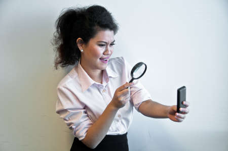 Business woman examine mobile phone by magnifierの写真素材