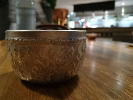 Silver traditional water bowl cup Thailand style on wood tableの写真素材