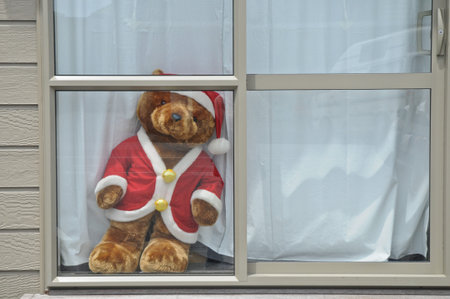 Golden bear in Santa Claus dress standing on white wooden windowの写真素材