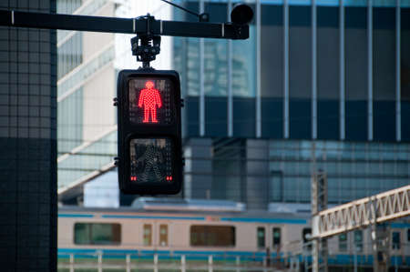 Red man stop traffic sign in front of Tokyo train stationの写真素材