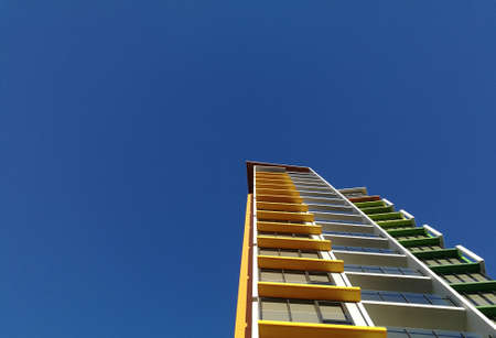 Modern high rise yellow apartment and blue skyの写真素材