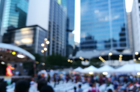 Defocused scene of crowd of people attending public concert celebrating New Year festival in city in Eveningの写真素材