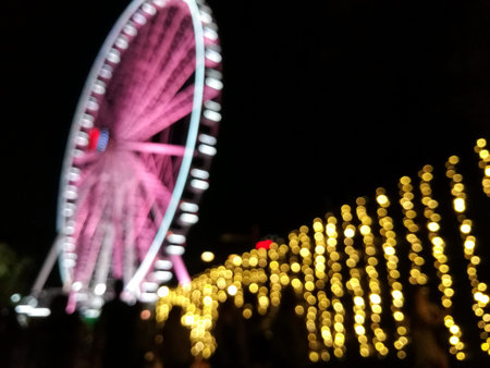 Defocused scene of giant pink flyer ferris wheel at night with yellow light fenceの写真素材