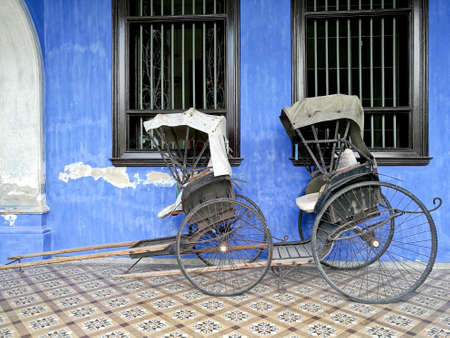 Old vintage traditional rickshaws in front of blue building in Penangの写真素材