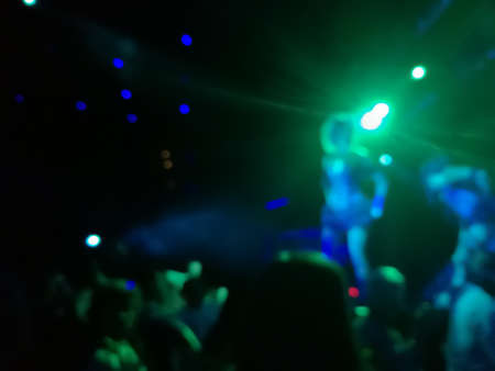 Defocused abstract blurred scene of musical light performance in a concert on stage with crowdの写真素材