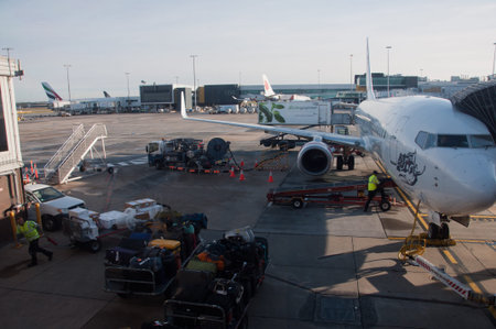 MELBOURNE, AUSTRALIA - JULY 26, 2018: Virgin Australia plane parks and luggages are offloaded at...