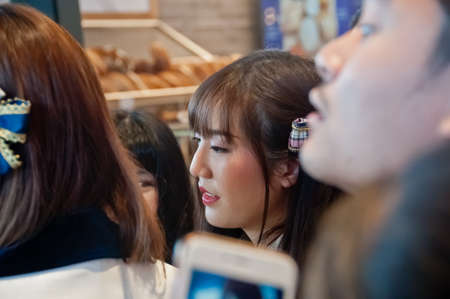 BANGKOK, THAILAND - NOVEMBER 23, 2018: Dusita Kitisarakulchai (Natherine), a member of Thai Idol girl group BNK48, looks with curiosity to see  fanclub in Gontran Cherrier bakery grand opening public event. There are many fanclub takes photos of her in thのeditorial素材