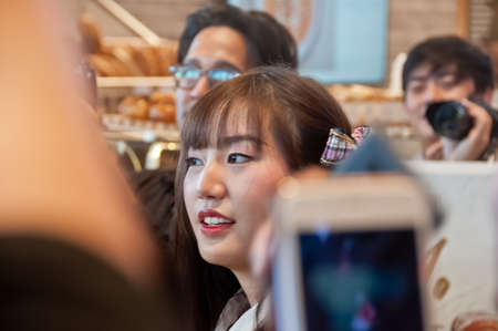 BANGKOK, THAILAND - NOVEMBER 23, 2018: Dusita Kitisarakulchai (Natherine), a member of Thai Idol girl group BNK48, looks with curiosity to see  fanclub in Gontran Cherrier bakery grand opening public event. There are many fanclub takes photos of her in thのeditorial素材