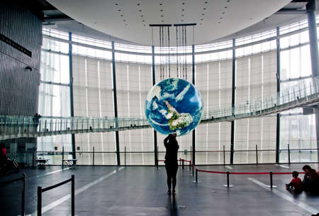 TOKYO, JAPAN - DECEMBER 2, 2018: Miraikan National Museum of Emerging Science and Innovation. The Geo-Cosmos floating earthsphere displays rendition of earth surface by 10 million pixels of organic LED panels. There are  visitors taking photos and sit on のeditorial素材