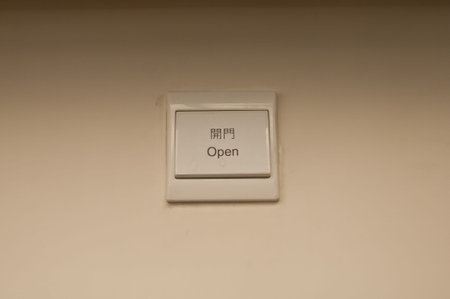 White plastic light electric switch in English and Chinese on white plain wall