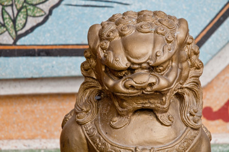 Strong and majestic golden dark bronze Asian Chinese lion metalic statue in a templeの写真素材