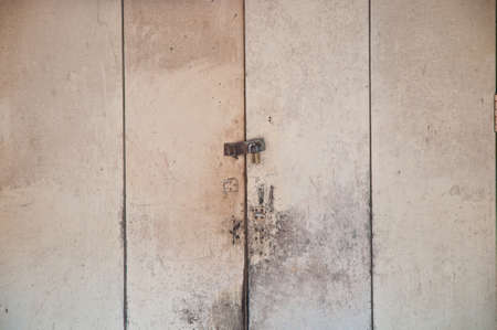 Locked key of wooden grey white door panes of an old houseの写真素材