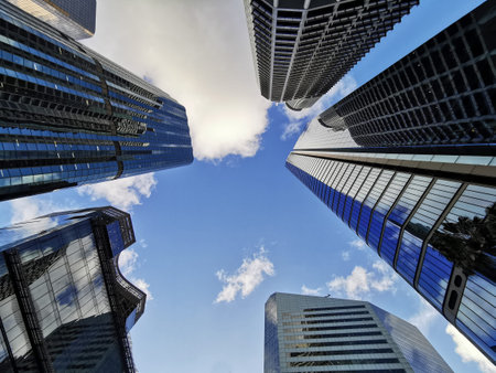 Lookup view of variety of corporate business high-rise skyscrapers buildings with blue bright sky in...