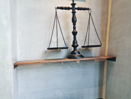 Black balance traditional weighing scale placed on the wooden shelf with white granite wallの写真素材