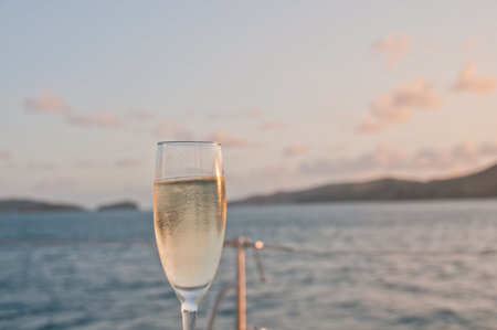 Bubby sparkling champagne flute glass with evening scene while sailing in the Pacific Ocean in Queensland Australiaの写真素材