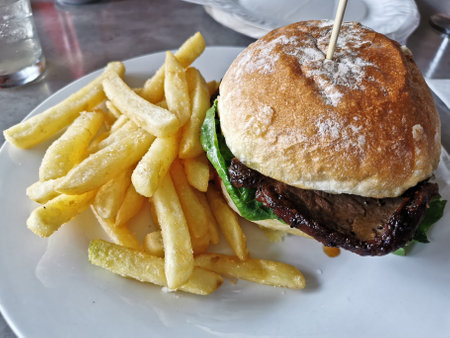 Chargrilled thin beef steak burger with golden beer-battered french fries chipsの写真素材