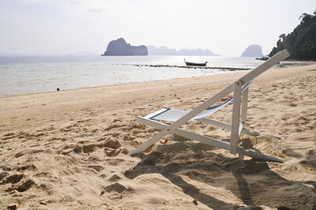 Relax foldable beach chair on sandy seashore in sunny dayの写真素材
