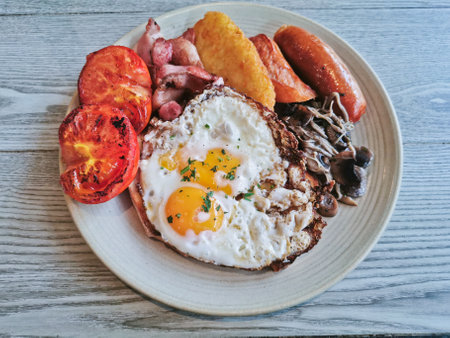 English Big Breakfast with sunny fried eggs, sausage, bacon, tomatos, hash brown, mushroomの写真素材