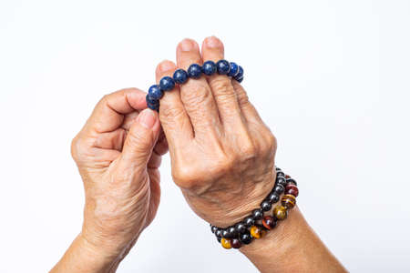 Senior woman's hand wearing supplement good fortune colorful bracelets isolated on white backgroundの写真素材