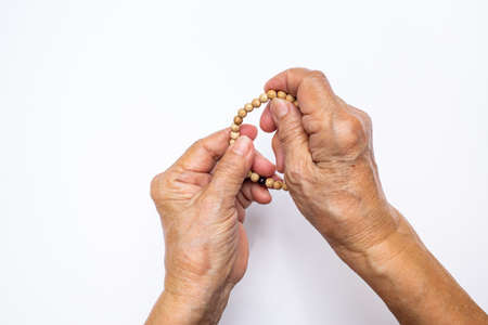 Senior woman's hand counting buddha bead bracelet on white backgroundの写真素材