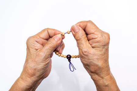 Senior woman's hand counting buddha bead bracelet on white backgroundの写真素材