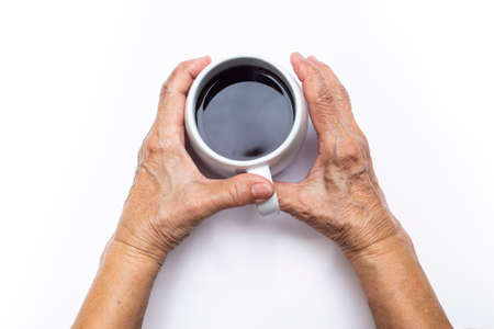 Senior woman's hand hold black coffee cup isolated on white backgroundの写真素材