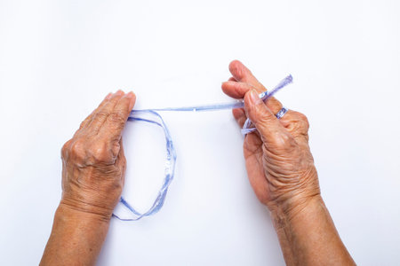 Senior woman's hands pulling blue plastic rope on white backgroundの写真素材