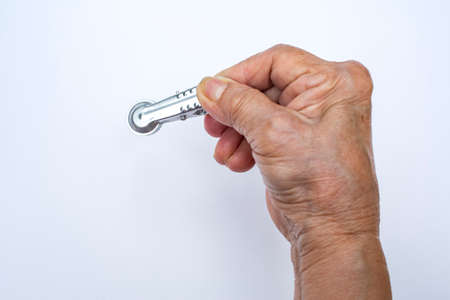 Senior woman's hand squeezing clothes peg on white background, Close up shot, Selective focusの写真素材