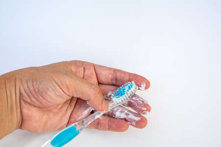 Woman's left hand squeezing toothpaste on brush against isolated on white backgroundの写真素材