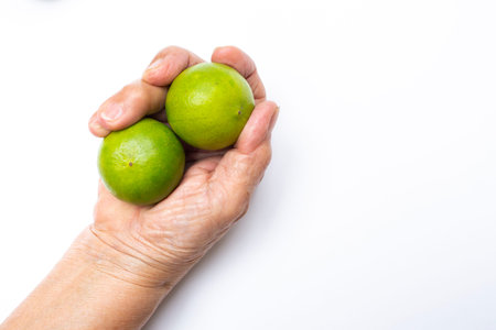 Senior woman's hand holding limes isolated on white background