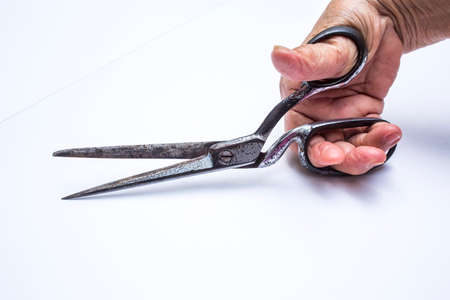 Senior woman's hands holding scissors isolated on white background, About tailorの写真素材