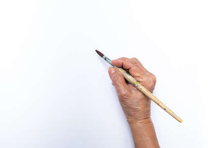 Senior woman's hand painting with paintbrush isolated on white backgroundの写真素材