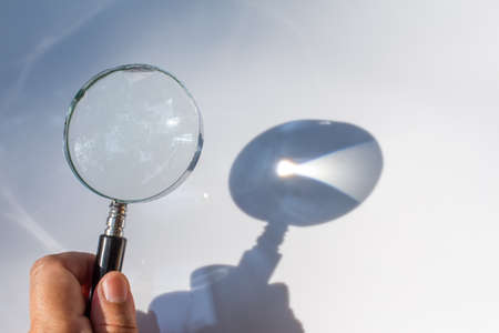 Left hand holding old magnifying glass on white background, Light and Shadowの写真素材