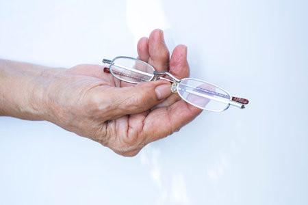 Old woman hand hold  longsighted eye glasses   isolated on white background